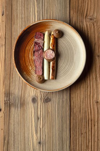 A vertical top view of a plate of sausages on a wooden background