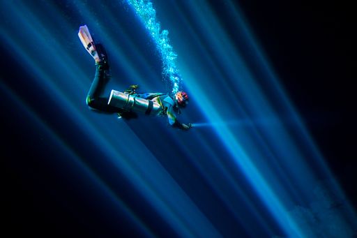 A breathtaking view of scuba diver with flashlight in the deep ocean