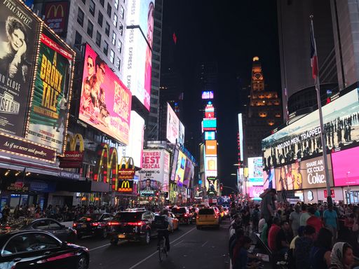 A low angle shot of Times Square billboards shining bright at night