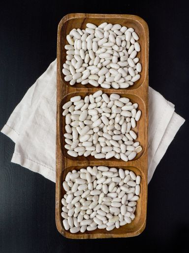 A top view of white beans in a wooden bowl on a table