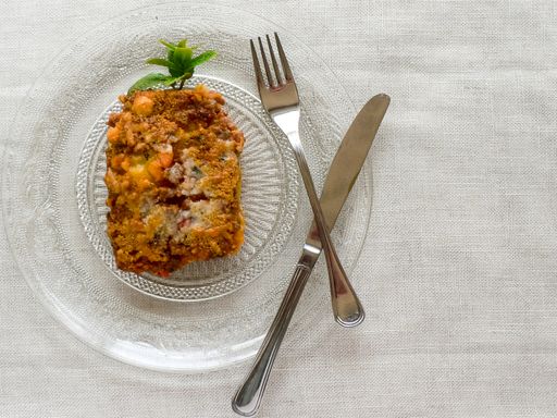 A top view of a delicious shepherd's pie on a plate with a silver fork and knife on the side