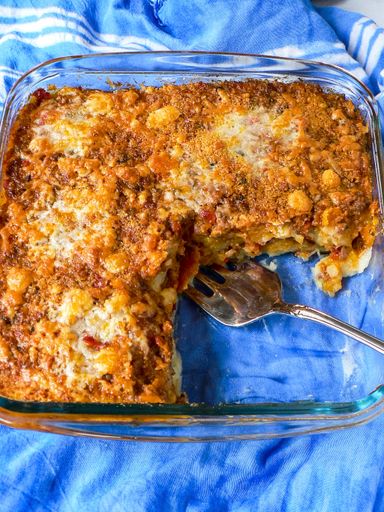 A high angle shot of delicious casserole in the pan with a fork places on a blue cloth