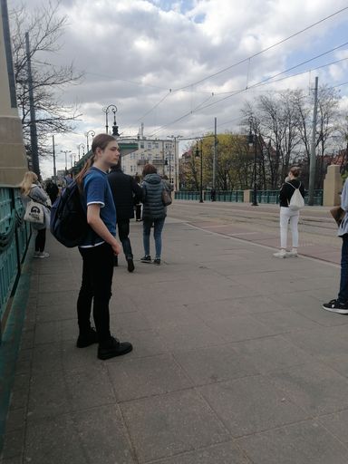 A vertical shot of a passengers waiting on a public transport tram stop in the Most Teatralny bridge