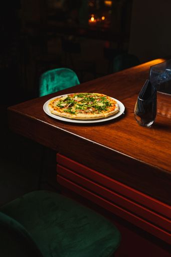 A vertical shot of pizza with prosciutto on a wooden bar counter