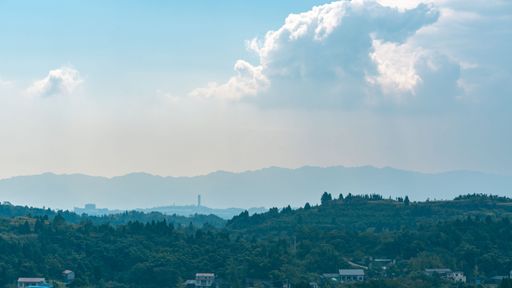 View of a village on green hills with silhouettes of mountains in the background