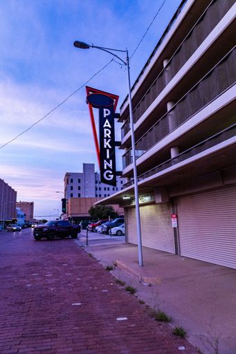 A vertical shot of a parking sign in front of the private garage against the blue sky. Lubbock, Texas.
