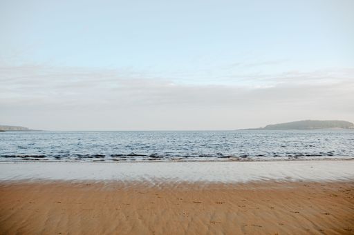 A beautiful shot of the new river beach with the seascape in daylight under the blue cloudy sky in New Brunswick, Canada