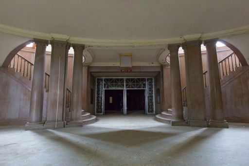 The entrance gate of a big building with marble columns in the design and two sides stairs