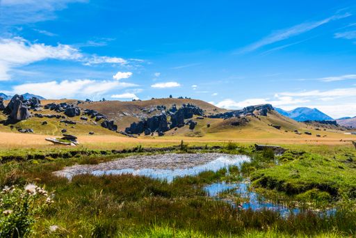 A scenic view of a wetland in the background of hills and mountains in Cave Stream Scenic Reserve, South Island, New Zealand