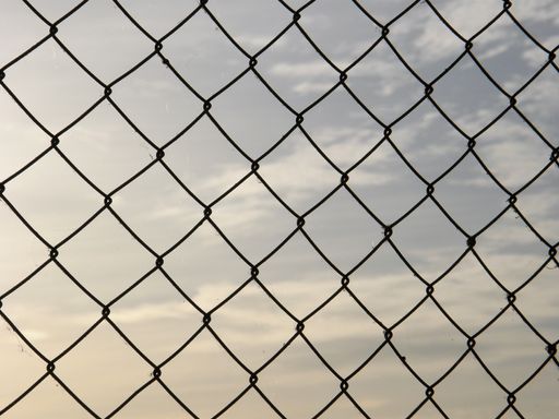 A wire fence against a cloudy sky