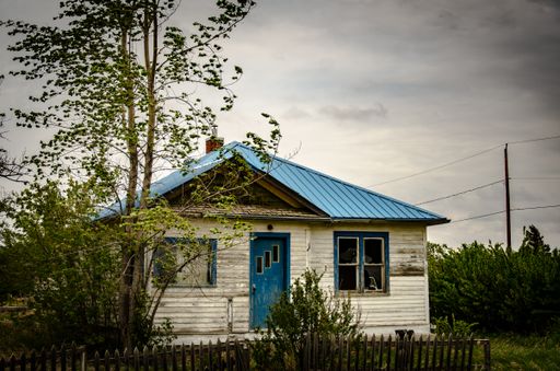 A creepy, old and aged abandoned wooden house in a field under the cloudy and rainy sky
