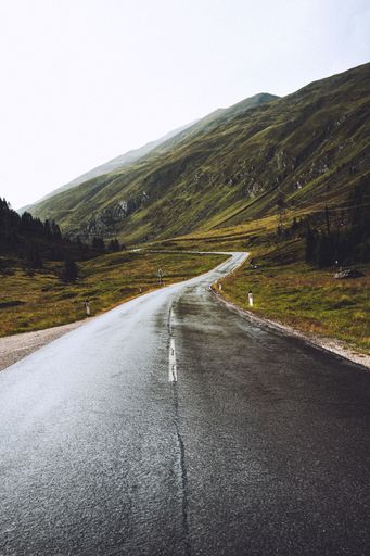 A vertical shot of a wet asphalt road with a crack in the middle on it