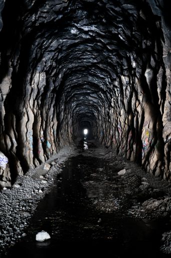 A vertical shot of the inside the Donner Summit China Wall tunnel with a light in the end of it