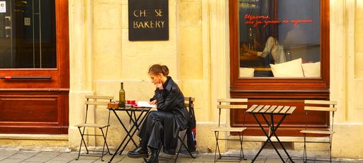 Lady enjoying wine and reading a book at an outdoor cafe