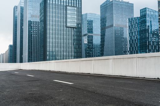 A closeup of an empty asphalt road with modern office buildings in downtown during daytime