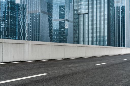A closeup of an empty asphalt road with modern office buildings in downtown during daytime