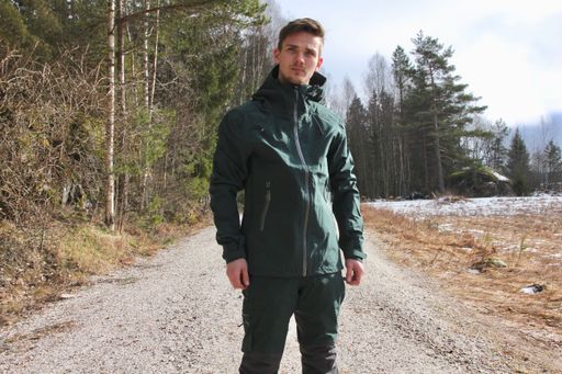 A young Caucasian hiker standing on a sand road surrouned by trees
