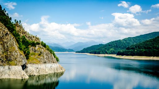 A picturesque view of Vidraru Lake surrounded by lush forests in Arges County, Romania