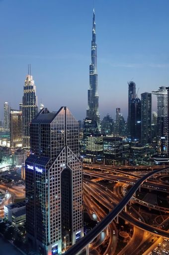High angle selective focus cityscape of Dubai with Dusit Thani hotel in the foreground and Burj Khalifa in the background.