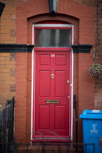 A vertical shot of a red door of a residential building