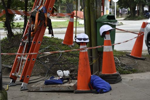 A white hard hat on top of a safety cone with extension ladder on a sidewalk