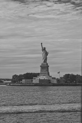 A vertical shot of the Statue of Liberty, Manhattan, New York City, NY, United States with a gray cloudy sky