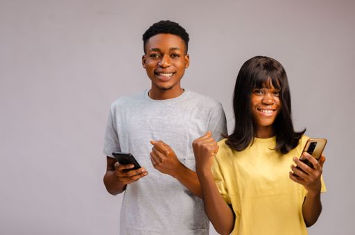 A Happy excited and happy African Couple standing and using phones isolated on gray background