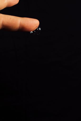 single bubble hanging downwards from outstretched finger on black background with copy space