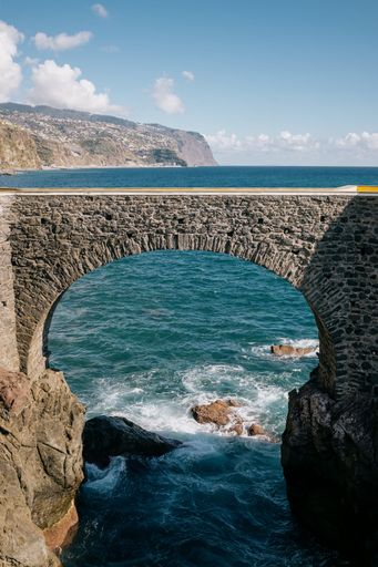 A vertical shot of a stone arch over water in Madeira, Portugal