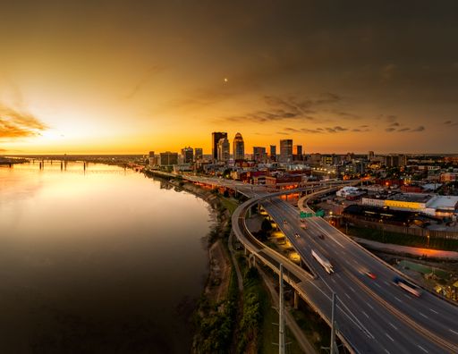 An aerial scene of night long exposure of a bridge over water with cars in Louisville, Kentucky, USA with a sunset sky