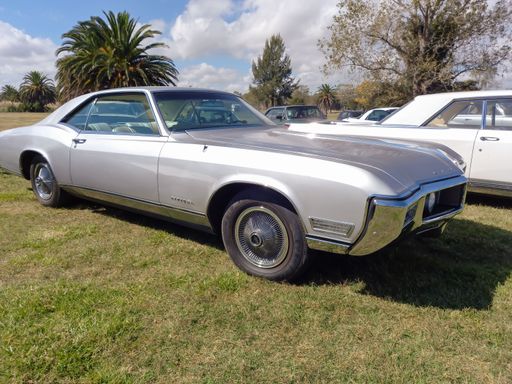 Old silver gray Buick Riviera coupe hardtop Second Generation 1966 - 1969 by GM parked on the grass. Classic luxury car. Copyspace