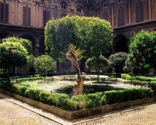 A yard with many trees in front of on old house in the Rome downtown in Italy