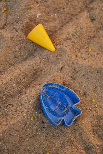 Vertical shot of a yellow cone and a blue fish beach toys on sand