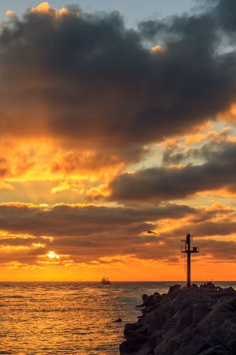 A vertical shot of a cloudy sunset at the gates to the port of Klaipeda, Lithuania