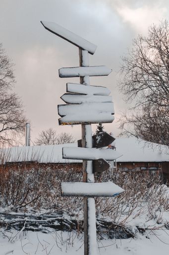 A vertical shot of the snowy wooden pole with direction signs. Beach in Jurmala, Latvia.