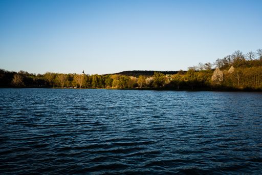 A beautiful view of a lake among trees under the blue sky