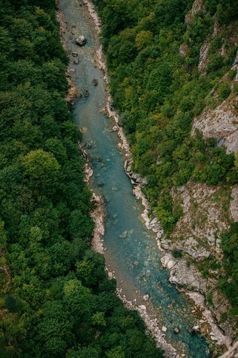 A vertical high angle shot of a narrow rocky river in Montenegro surrounded by a lush forest