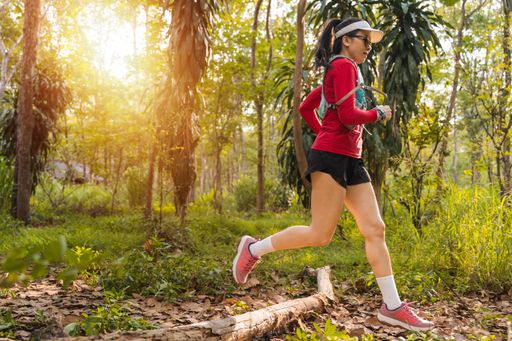 A closeup of a Young fitness sportswoman running in the tropical forest park in the evening
