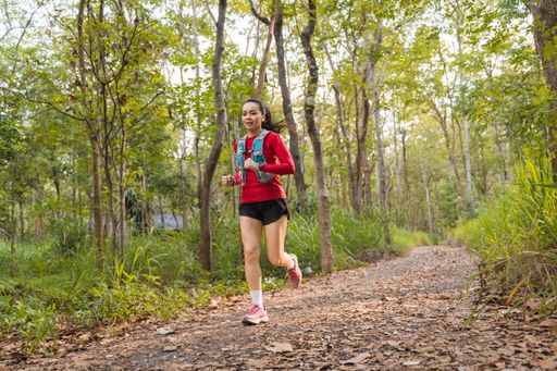 A closeup of a Young fitness sportswoman running in the tropical forest park in the evening