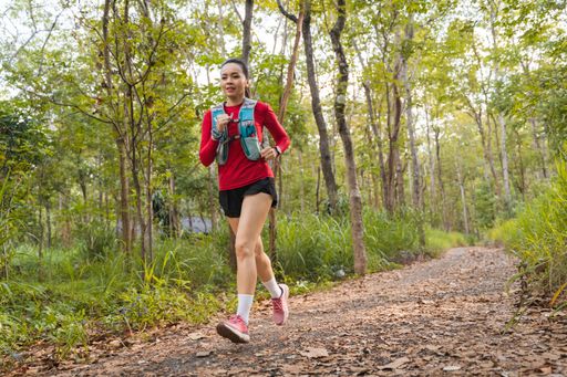A closeup of a Young fitness sportswoman running in the tropical forest park in the evening