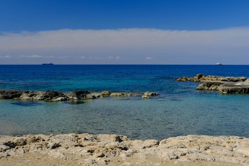 A beautiful view of the sea with ships on the horizon from the rocky shore