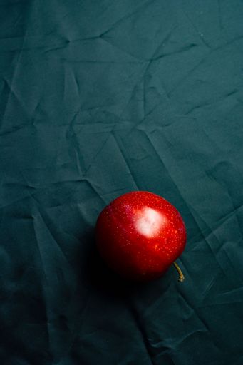A top view of a red apple on a blue surface