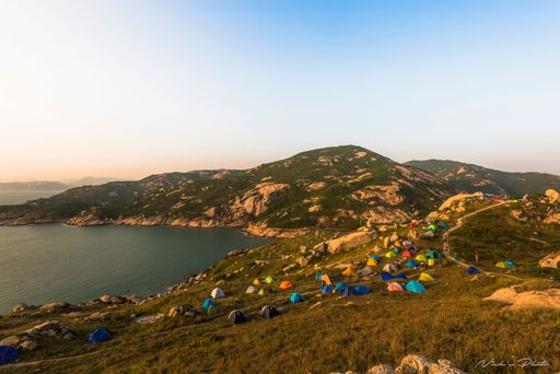 Hong Kong ,Po Toi Island surrounded by the sea , tourists with colorful tents are located on the rocks of the island at sunset
