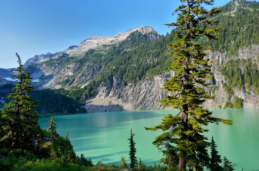 A mesmerizing view of a calm lake surrounded by green vegetation with mountains in the background