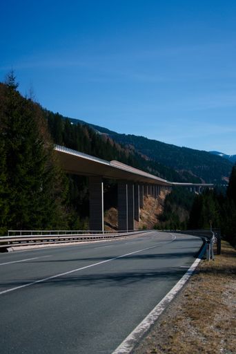 A beautiful view of an empty road and a bridge under the blue sky