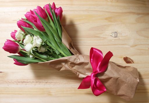 A top view of a bouquet with pink tulips and white roses on a wooden table