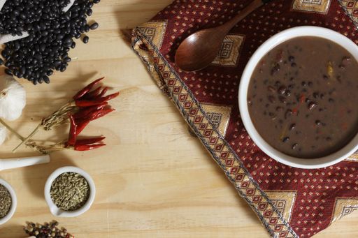 A top view of black bean soup with ingredients on a wooden table