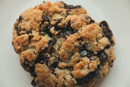 An overhead shot of a dark chocolate oatmeal cookie on a white background