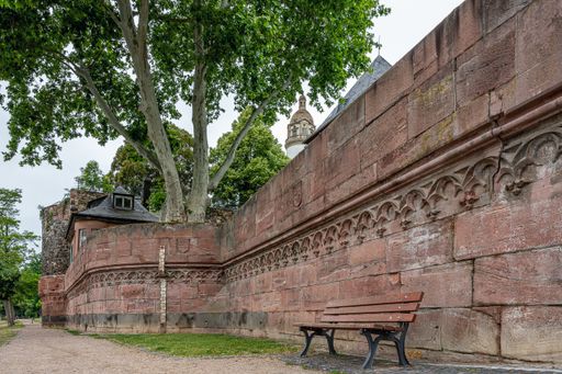 A facade of the castle with a wooden bench on the foreground at daytime