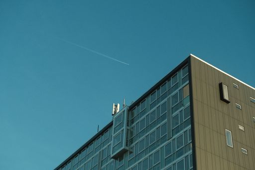 An apartment building wit han airplane flying over at golden hour on a winter day.